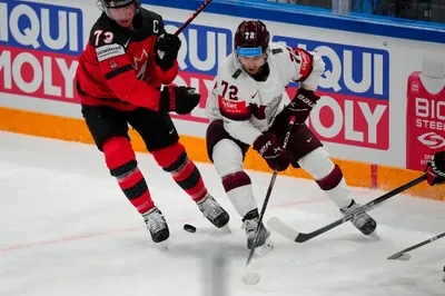 Latvia's Janis Jaks (72) battles near the boards with Canada's Tyler Toffoli (73) during their semifinal match at the Ice Hockey World Championship in Tampere, Finland, Saturday, May 27, 2023. (AP Photo/Pavel Golovkin)