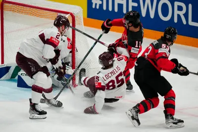 Latvia's Dans Locmelism (85) falls to the ice defending the net against Canada's Jack McBain (11) and Michael Carconem (53) during their semifinal match at the Ice Hockey World Championship in Tampere, Finland, Saturday, May 27, 2023. (AP Photo/Pavel Golovkin)