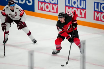 Canada's Jack Quinn (22) moves the puck against Latvia's Rodrigo Abols (18) during their semifinal match at the Ice Hockey World Championship in Tampere, Finland, Saturday, May 27, 2023. (AP Photo/Pavel Golovkin)