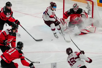 Latvia's Dans Locmelis (85) shoots past Canada's goalie Samuel Montembeault and Latvia's Janis Jaks (72) during their semifinal match at the Ice Hockey World Championship in Tampere, Finland, Saturday, May 27, 2023. (AP Photo/Pavel Golovkin)