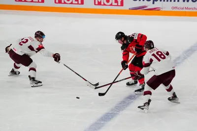 Canada's Tyler Toffoli (73) passes between Latvia's Karlis Cukste (2) and Rodrigo Abols (18) during their semifinal match at the Ice Hockey World Championship in Tampere, Finland, Saturday, May 27, 2023. (AP Photo/Pavel Golovkin)