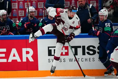 Latvia's Rodrigo Abols (18) battles along the boards with United States Rocco Grimaldi (56) in their bronze medal match at the Ice Hockey World Championship in Tampere, Finland, Sunday, May 28, 2023. (AP Photo/Pavel Golovkin)