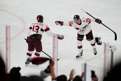 Latvia's Miks Indrasis (70) and Rihards Bukarts (13) celebrate a goal by Janis Jaks, not pictured, in their bronze medal match against the United States at the Ice Hockey World Championship in Tampere, Finland, Sunday, May 28, 2023. (AP Photo/Pavel Golovkin)