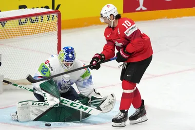 Andres Ambuhl of Switzerland, right, fights for a puck with goalie Gasper Kroselj of Slovenia during the group B match between Switzerland and Slovenia at the ice hockey world championship in Riga, Latvia, Saturday, May 13, 2023. (AP Photo/Roman Koksarov)