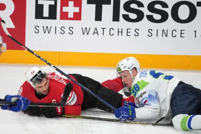 Nino Niederreiter of Switzerland, right, fights for a puck with Blaz Tomazevic of Slovenia during the group B match between Switzerland and Slovenia at the ice hockey world championship in Riga, Latvia, Saturday, May 13, 2023. (AP Photo/Roman Koksarov)