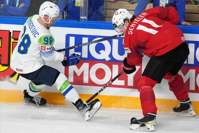 Sven Senteler of Switzerland, right, fights for a puck with Blaz Tomazevic of Slovenia during the group B match between Switzerland and Slovenia at the ice hockey world championship in Riga, Latvia, Saturday, May 13, 2023. (AP Photo/Roman Koksarov)
