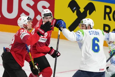 Nino Niederreiter, left, and Dario Simion, centre, of Switzerland, right, fight for a puck with Miha Stebih of Slovenia during the group B match between Switzerland and Slovenia at the ice hockey world championship in Riga, Latvia, Saturday, May 13, 2023. (AP Photo/Roman Koksarov)
