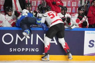 Blaz Tomazevic of Slovenia, left, fights for a puck with Tyler Myers of Canada during the group B match between Slovenia and Canada at the ice hockey world championship in Riga, Latvia, Sunday, May 14, 2023. (AP Photo/Roman Koksarov)