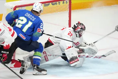 Milos Kelemen of Slovenia, left, fights for a puck with goalie Scott Laughton of Canada during the group B match between Slovenia and Canada at the ice hockey world championship in Riga, Latvia, Sunday, May 14, 2023. (AP Photo/Roman Koksarov)
