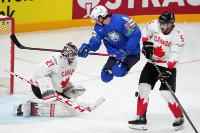 Ziga Jeglic of Slovenia, centre, fights for a puck with goalie Scott Laughton and Jacob Middleton, right, of Canada during the group B match between Slovenia and Canada at the ice hockey world championship in Riga, Latvia, Sunday, May 14, 2023. (AP Photo/Roman Koksarov)