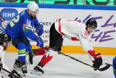 Nik Simsic of Slovenia, left, fights for a puck with Jack McBain of Canada during the group B match between Slovenia and Canada at the ice hockey world championship in Riga, Latvia, Sunday, May 14, 2023. (AP Photo/Roman Koksarov)