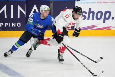 Blaz Tomazevic of Slovenia, left, fights for a puck with Milan Lucic of Canada during the group B match between Slovenia and Canada at the ice hockey world championship in Riga, Latvia, Sunday, May 14, 2023. (AP Photo/Roman Koksarov)