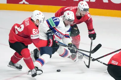 Eirik Salsten of Norway, centre, fights for a puck with Denis Malgin, left, and Andrea Glauser of Switzerland during the group B match between Norway and Switzerland at the ice hockey world championship in Riga, Latvia, Sunday, May 14, 2023. (AP Photo/Roman Koksarov)