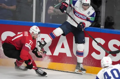 Mathias Trettenes of Norway, right, fights for a puck with Tanner Richard of Switzerland during the group B match between Norway and Switzerland at the ice hockey world championship in Riga, Latvia, Sunday, May 14, 2023. (AP Photo/Roman Koksarov)