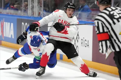 Mario Grman of Slovakia, left, fights for a puck with Peyton Krebs of Canada during the group B match between Slovakia and Canada at the ice hockey world championship in Riga, Latvia, Monday, May 15, 2023. (AP Photo/Roman Koksarov)