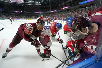 Miks Indrasis of Latvia, left, fights for a puck with Jiri Cernoch of Czech Republic, centre, during the group B match between Latvia and Czech Republic at the ice hockey world championship in Riga, Latvia, Monday, May 15, 2023. (AP Photo/Roman Koksarov)