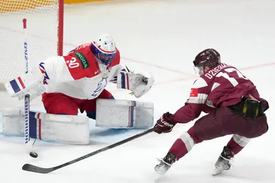 Martins Dzierkals of Latvia, right, fights for a puck with goalie Simon Hrubec of Czech Republic during the group B match between Latvia and Czech Republic at the ice hockey world championship in Riga, Latvia, Monday, May 15, 2023. (AP Photo/Roman Koksarov)
