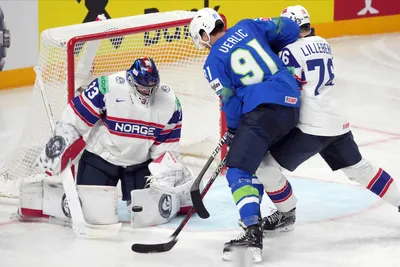 Miha Verlic of Slovenia, right, fights for a puck with goalie Henrik Haukeland of Norway during the group B match between Slovenia and Norway at the ice hockey world championship in Riga, Latvia, Tuesday, May 16, 2023. (AP Photo/Roman Koksarov)