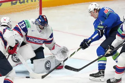 Jan Drozd of Slovenia, right, fights for a puck with goalie Henrik Haukeland of Norway during the group B match between Slovenia and Norway at the ice hockey world championship in Riga, Latvia, Tuesday, May 16, 2023. (AP Photo/Roman Koksarov)