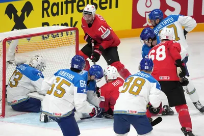 Tanner Richard of Switzerland, centre, fights for a puck with goalie Andrey Shutov of Kazakhstan, left, during the group B match between Switzerland and Kazakhstan at the ice hockey world championship in Riga, Latvia, Tuesday, May 16, 2023. (AP Photo/Roman Koksarov)