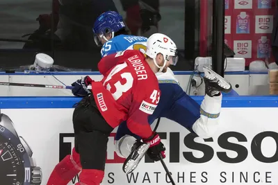 Andrea Glauser of Switzerland, front, fights for a puck with Samat Daniyar of Kazakhstan during the group B match between Switzerland and Kazakhstan at the ice hockey world championship in Riga, Latvia, Tuesday, May 16, 2023. (AP Photo/Roman Koksarov)