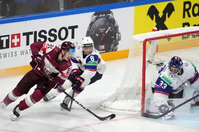 Rudolfs Balcers of Latvia, left, fights for a puck with Norway goalie Henrik Haukeland, right, and Mathias Trettenes, center, during the group B match between Latvia and Norway at the ice hockey world championship in Riga, Latvia, Wednesday, May 17, 2023. (AP Photo/Roman Koksarov)