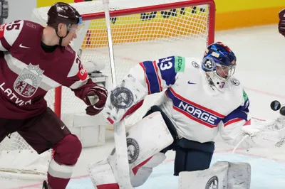 Andris Dzerins of Latvia, left, fights for a puck with goalie Henrik Haukeland of Norway during the group B match between Latvia and Norway at the ice hockey world championship in Riga, Latvia, Wednesday, May 17, 2023. (AP Photo/Roman Koksarov)