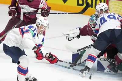 Goalie Arturs Silovs of Latvia, centre, fights for a puck with Thomas Berg-Paulsen, left, ans Christian Kaasastul, right of Norway during the group B match between Latvia and Norway at the ice hockey world championship in Riga, Latvia, Wednesday, May 17, 2023. (AP Photo/Roman Koksarov)