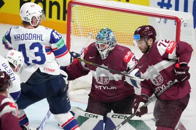 Goalie Arturs Silovs, centre, and Janis Jaks, right, of Latvia fight for a puck with Max Krogdahl, left of Norway during the group B match between Latvia and Norway at the ice hockey world championship in Riga, Latvia, Wednesday, May 17, 2023. (AP Photo/Roman Koksarov)