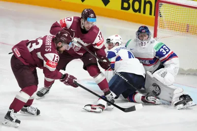 Rihards Bukarts, left, Martins Dzierkals, second left. of Latvia, fight for a puck with Johannes Johannesen, centre, and goalie Henrik Haukeland of Norway during the group B match between Latvia and Norway at the ice hockey world championship in Riga, Latvia, Wednesday, May 17, 2023. (AP Photo/Roman Koksarov)