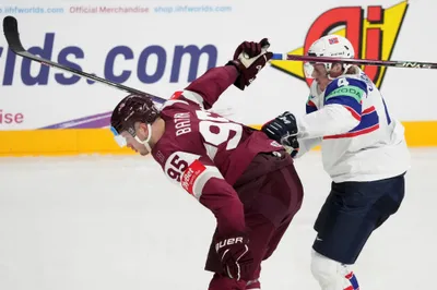 Oskars Batna of Latvia, left, fights for a puck with Johannes Johannesen of Norway during the group B match between Latvia and Norway at the ice hockey world championship in Riga, Latvia, Wednesday, May 17, 2023. (AP Photo/Roman Koksarov)