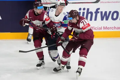 Martins Dzierkals, left, and Roberts Bukarts, right, of Latvia fight for a puck with Ole Einar Andersen of Norway during the group B match between Latvia and Norway at the ice hockey world championship in Riga, Latvia, Wednesday, May 17, 2023. (AP Photo/Roman Koksarov)