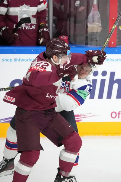 Toms Andersons of Latvia, left, fights for a puck with Johannes Johannesen of Norway during the group B match between Latvia and Norway at the ice hockey world championship in Riga, Latvia, Wednesday, May 17, 2023. (AP Photo/Roman Koksarov)