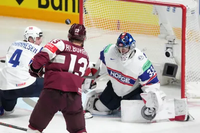 Rihards Bukarts of Latvia, centre, makes a shot past the goalie Henrik Haukeland of Norway during the group B match between Latvia and Norway at the ice hockey world championship in Riga, Latvia, Wednesday, May 17, 2023. (AP Photo/Roman Koksarov)