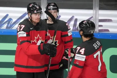 Lawson Crouse, left, Jack Quinn, centre, and Ethan Bear celebrate a goal, right, fights for a puck with of Kazakhstan during the group B match between Canada and Kazakhstan at the ice hockey world championship in Riga, Latvia, Wednesday, May 17, 2023. (AP Photo/Roman Koksarov)