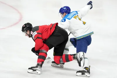 Cody Glass of Canada, left, fights for a puck with Madi Dikhanbek of Kazakhstan during the group B match between Canada and Kazakhstan at the ice hockey world championship in Riga, Latvia, Wednesday, May 17, 2023. (AP Photo/Roman Koksarov)