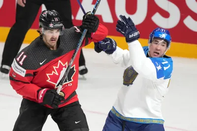 Jack McBain of Canada, left, fights for a puck with Madi Dikhanbek of Kazakhstan during the group B match between Canada and Kazakhstan at the ice hockey world championship in Riga, Latvia, Wednesday, May 17, 2023. (AP Photo/Roman Koksarov)