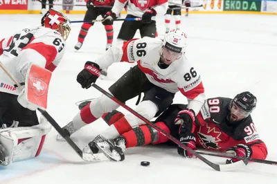 Goalie Leonardo Genoni, left, and Janis Moser, centre of Switzerland, fight for a puck with Joe Veleno of Canada during the group B match between Switzerland and Canada at the ice hockey world championship in Riga, Latvia, Saturday, May 20, 2023. (AP Photo/Roman Koksarov)