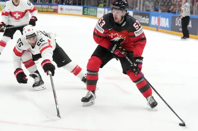 Romain Loeffel of Switzerland, left, fights for a puck with Michael Carcone of Canada during the group B match between Switzerland and Canada at the ice hockey world championship in Riga, Latvia, Saturday, May 20, 2023. (AP Photo/Roman Koksarov)