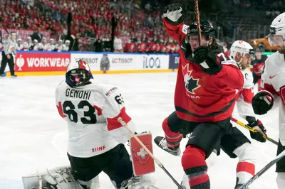 Goalie Leonardo Genoni of Switzerland, left, fights for a puck with Tyler Toffoli of Canada during the group B match between Switzerland and Canada at the ice hockey world championship in Riga, Latvia, Saturday, May 20, 2023. (AP Photo/Roman Koksarov)