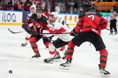 Tanner Richard of Switzerland, centre, fights for a puck with Jake Neighbours, left, and Pierre-Olivier Joseph of Canada during the group B match between Switzerland and Canada at the ice hockey world championship in Riga, Latvia, Saturday, May 20, 2023. (AP Photo/Roman Koksarov)