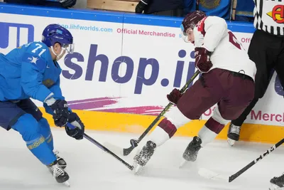 Toms Andersons of Latvia, right, fights for a puck with Madi Dikhanbek of Kazakhstan during the group B match between Kazakhstan and Latvia at the ice hockey world championship in Riga, Latvia, Saturday, May 20, 2023. (AP Photo/Roman Koksarov)