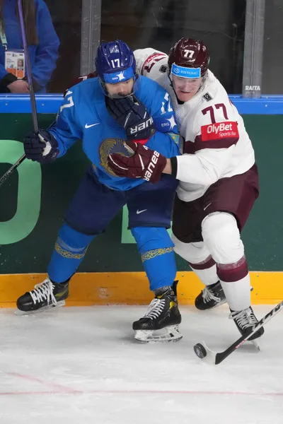 Kristaps Zile of Latvia, right, fights for a puck with Alikhan Omirbekov of Kazakhstan during the group B match between Kazakhstan and Latvia at the ice hockey world championship in Riga, Latvia, Saturday, May 20, 2023. (AP Photo/Roman Koksarov)