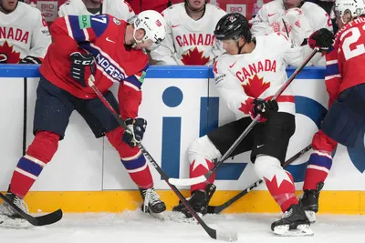 Ethan Bear of Canada, right, fights for a puck with Eirik Salsten, left, of Norway during the group B match between Canada and Norway at the ice hockey world championship in Riga, Latvia, Monday, May 22, 2023. (AP Photo/Roman Koksarov)