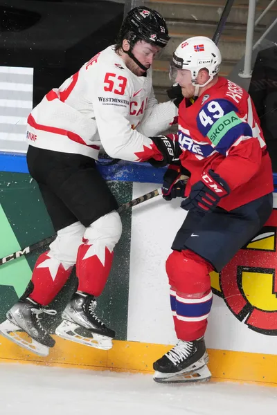 Michael Carcone of Canada, left, fights for a puck with Christian Kaasastul of Norway during the group B match between Canada and Norway at the ice hockey world championship in Riga, Latvia, Monday, May 22, 2023. (AP Photo/Roman Koksarov)
