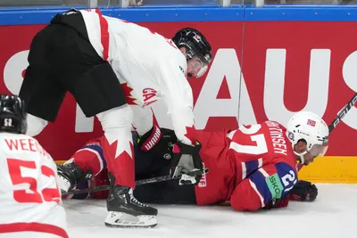 Jacob Middleton of Canada, left, fights for a puck with Andreas Martinsen of Norway during the group B match between Canada and Norway at the ice hockey world championship in Riga, Latvia, Monday, May 22, 2023. (AP Photo/Roman Koksarov)