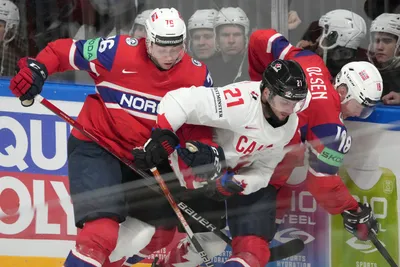 Scott Laughton of Canada, centre, fights for a puck with Emil Lilleberg, left, and Thomas Olsen, right, of Norway during the group B match between Canada and Norway at the ice hockey world championship in Riga, Latvia, Monday, May 22, 2023. (AP Photo/Roman Koksarov)