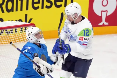 Goalie Andrey Shutov of Kazakhstan, left, fights for a puck with Nik Simsic of Slovenia during the group B match between Kazakhstan and Slovenia at the ice hockey world championship in Riga, Latvia, Monday, May 22, 2023. (AP Photo/Roman Koksarov)