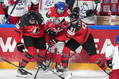 Milan Lucic, left, and Adam Fantilli, right of Canada fight for a puck with Daniel Vozenilek of Czech Republic during the group B match between Canada and Czech Republic at the ice hockey world championship in Riga, Latvia, Tuesday, May 23, 2023. (AP Photo/Roman Koksarov)