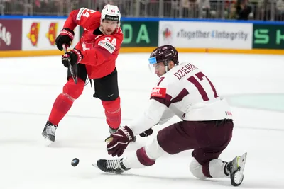 Martins Dzierkals of Latvia, right, fights for a puck with Christian Marti of Switzerland during the group B match between Latvia and Switzerland at the ice hockey world championship in Riga, Latvia, Tuesday, May 23, 2023. (AP Photo/Roman Koksarov)